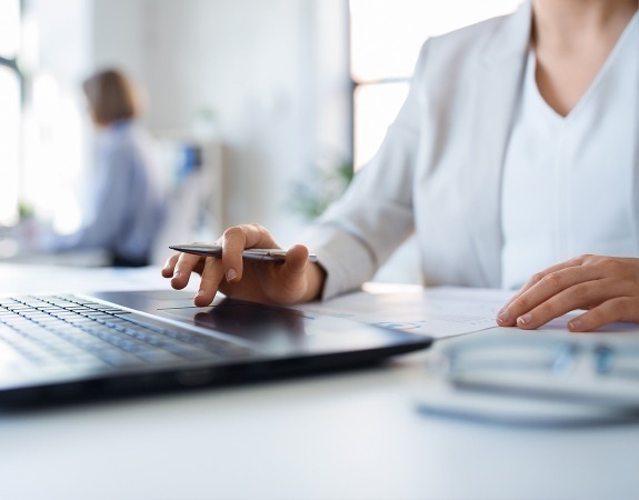 Person using laptop while holding a pen