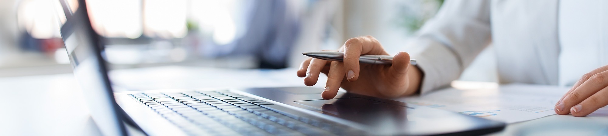 Person using a laptop with a pen in their hand