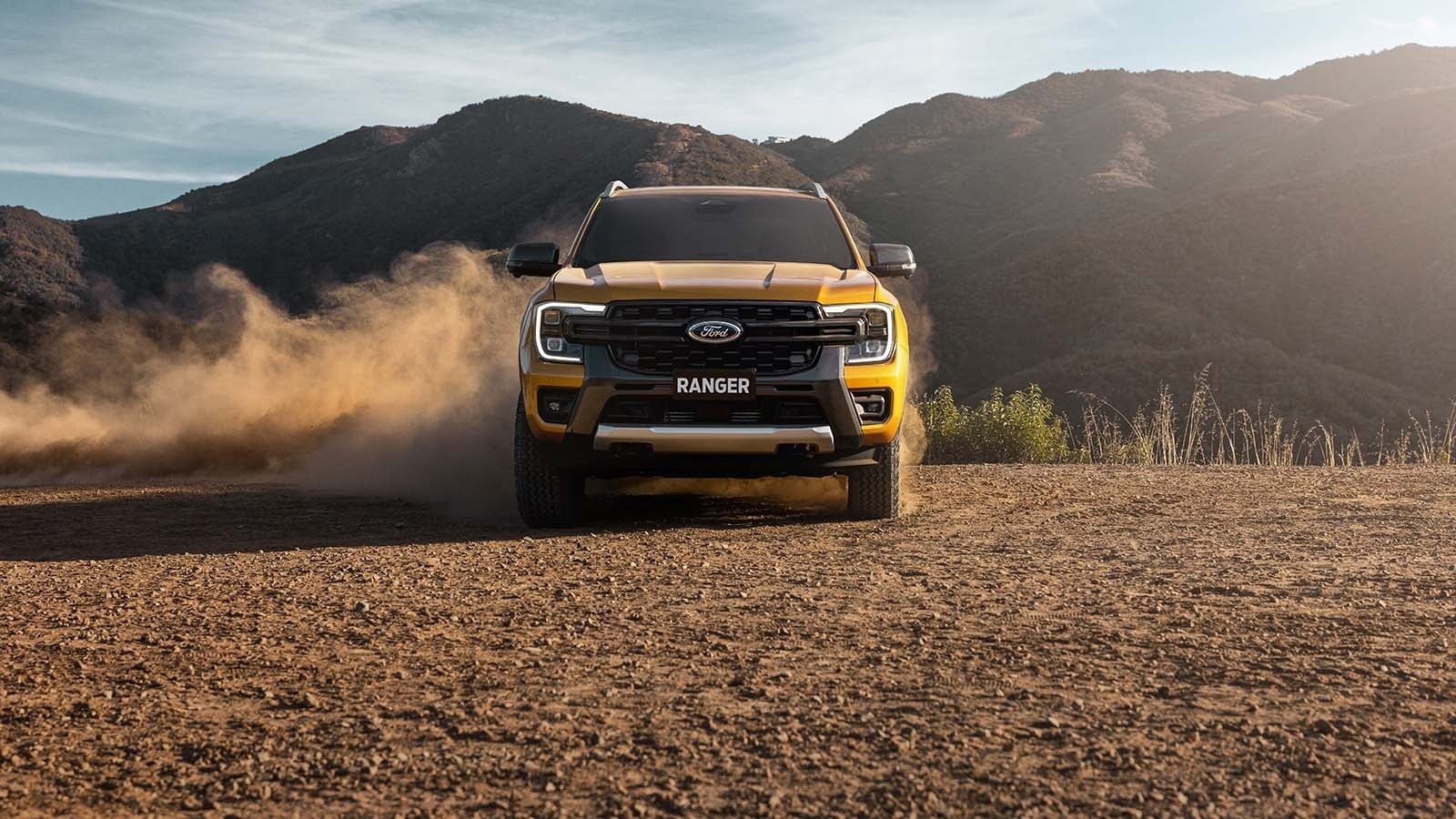 Ford Ranger on dirt track with mountains in the background